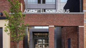 The exterior of AC Hotel Columbus with a brick facade, large glass entrance, and a tree in the foreground. - AC Hotel by Marriott Columbus Downtown (Columbus)