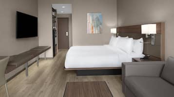 Une chambre d’hôtel moderne dotée d’un grand lit, d’une télévision à écran plat, d’un bureau et d’un canapé.