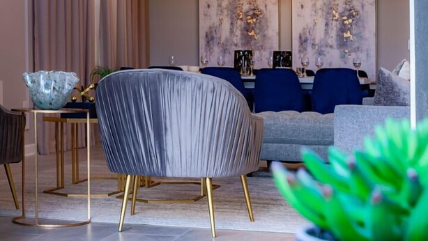 A modern living room with a sofa, a chair, and a dining table. - 801DSD: Stunning 5 Bedroom Villa - Private Pool and Spa with Nature View (Kissimmee)