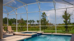 A covered outdoor swimming pool with lounge chairs and a view of the surrounding landscape. - 801DSD: Stunning 5 Bedroom Villa - Private Pool and Spa with Nature View (Kissimmee)