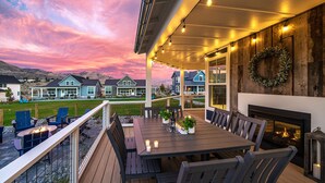 A covered outdoor patio with a dining table and chairs, a fire pit, and a fireplace. - Welcome to Don’t Stop Believin’ at Lake Chelan (Chelan)