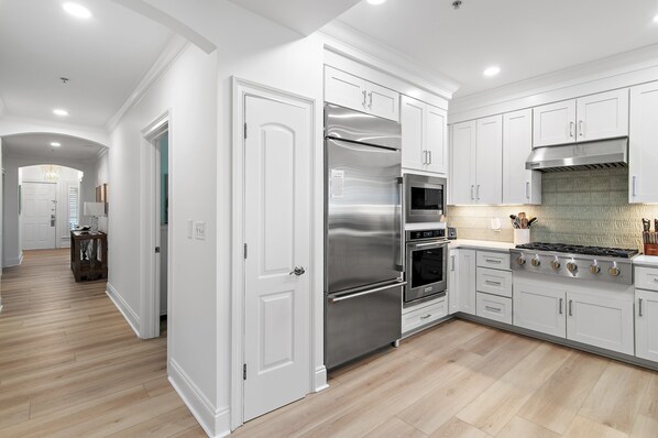 A modern kitchen with white cabinetry, stainless steel appliances, and a wooden floor. - Adagio B101 | Ground Floor Beach Front | Updated in 2026 | Resort Style Pool (Santa Rosa Beach)