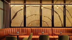 A restaurant with a patterned wall, leather booth seating, and green chairs. - The Forester Hotel, part of Unscripted by Hyatt (Lake Forest)