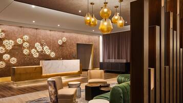 A modern lobby with a reception desk, seating area, and decorative lighting.