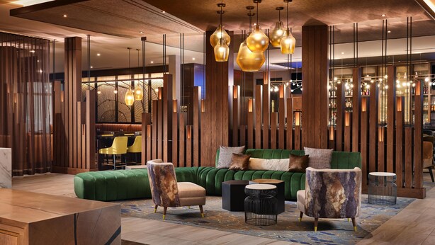 A modern interior with a green sofa, wooden accents, and pendant lighting. - The Forester Hotel, part of Unscripted by Hyatt (Lake Forest)