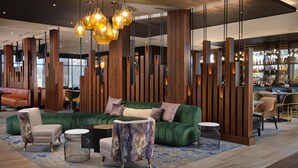 A modern lobby with a green sofa, seating, and a bar area. - The Forester Hotel, part of Unscripted by Hyatt (Lake Forest)