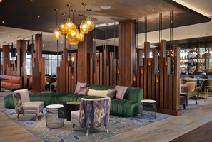 A modern lobby with a green sofa, seating, and a bar area. - The Forester Hotel, part of Unscripted by Hyatt (Lake Forest)