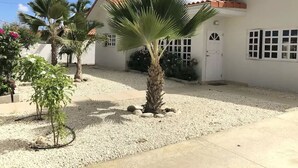 Ein weißes Gebäude mit rotem Dach, einem Kieshof und einer Palme.