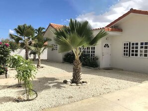 A white building with a red roof, a gravel courtyard, and a palm tree. - Sun, Fun & Family Time – Private Aruba Villa with Pool & Privacy (Oranjestad)