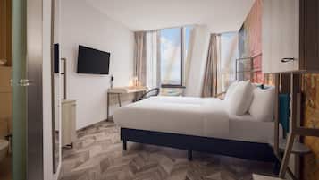 Une chambre d’hôtel avec un lit, un bureau, une chaise, une télévision et une fenêtre avec des rideaux.