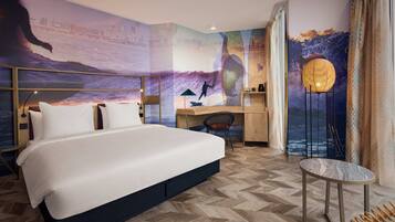 A modern hotel room with a large bed, a desk, and a chair.
