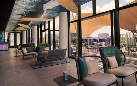 A modern indoor seating area with large windows, comfortable seating, and a ceiling mural.