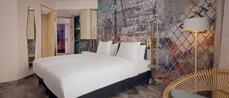 Quarto de hotel moderno com uma cama grande, uma cadeira de vime e um mural com vista para a cidade na parede.