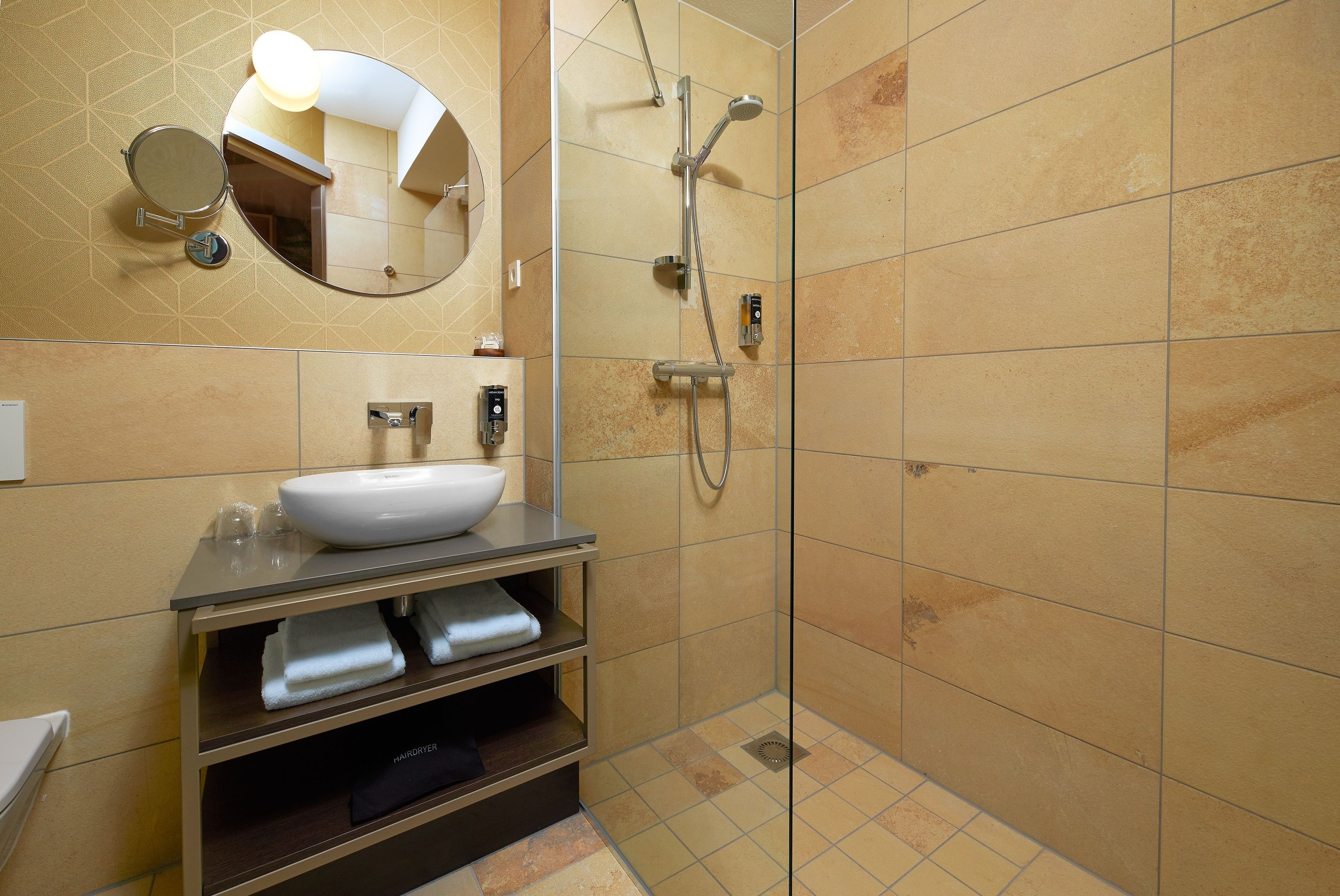 Ein modernes Badezimmer mit einem großen Spiegel, einem Waschbecken und einer Dusche.