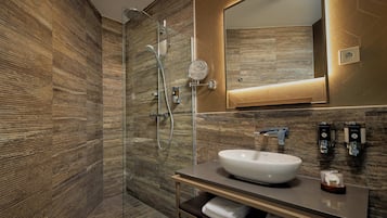Een moderne badkamer met een douchecabine van glas, een grote spiegel en een wastafel.