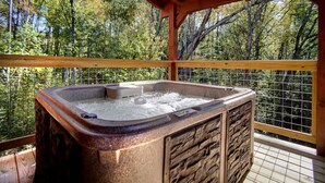 Ein Whirlpool auf einer Holzterrasse mit Blick auf einen Wald.