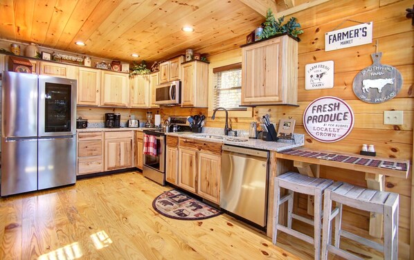 A wooden cabin-style kitchen with a refrigerator, stove, microwave, and wooden cabinets. There are signs on the wall advertising 'FARMER'S MARKET' and 'FRESH PRODUCE'. - TOOWAMBA - A Gem! - Secluded, Elegant-Award-Winning - Split payments 3 ways. (Gatlinburg)