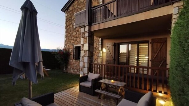 A two-story stone building with a balcony, outdoor seating, and a patio area.