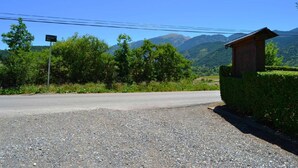 A rural road with a gravel shoulder, a signpost, and a wooden building with a sloped roof.