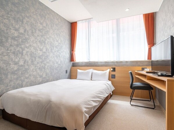 Una camera d'albergo con un letto, una scrivania e una televisione.