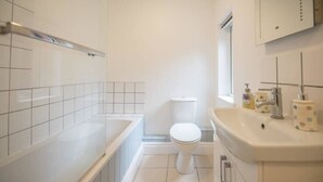 A bathroom with a bathtub, toilet, and sink.