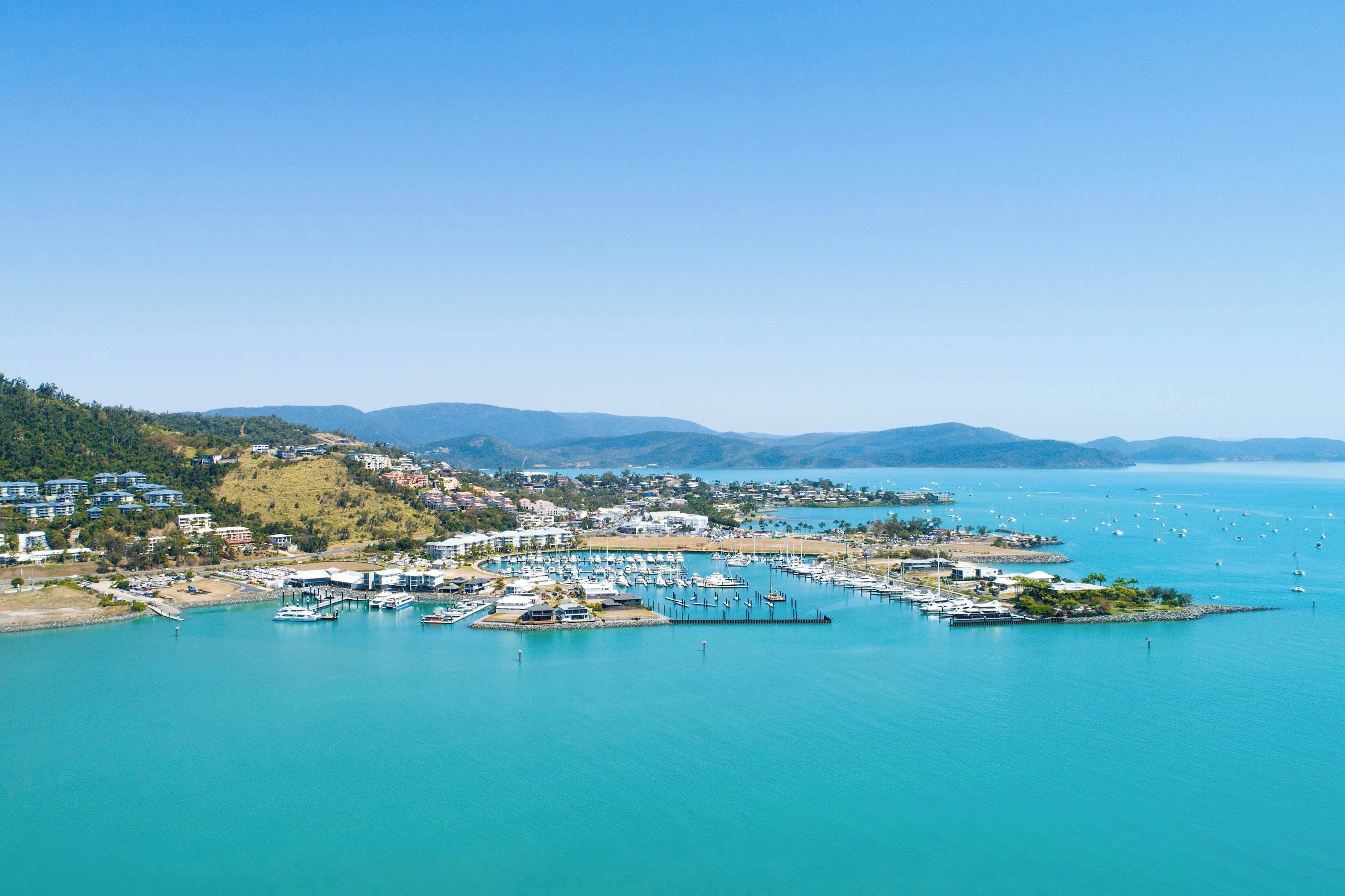 A coastal marina with boats, a pier, and residential buildings.