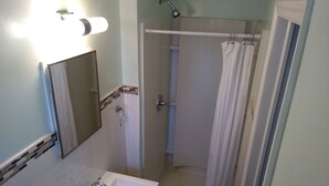 A bathroom with a white sink, a mirror, a shower with a glass door, and a towel rack. - Laurel Notch Motel (Bordentown)