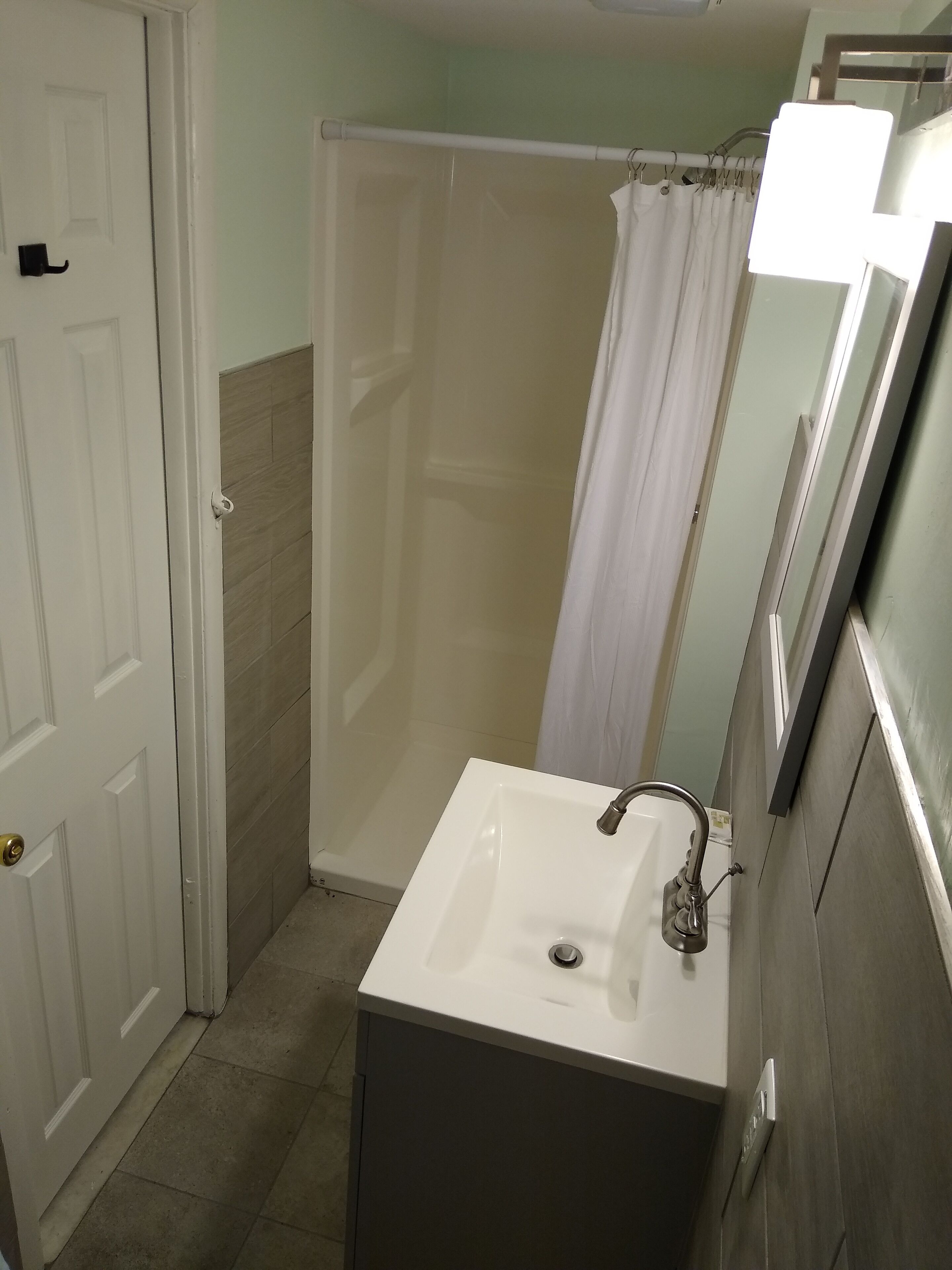 A bathroom with a white sink, a shower curtain, and a door.