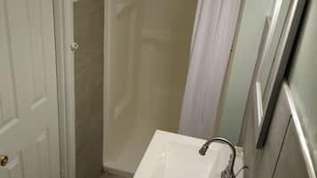 A bathroom with a white sink, a shower curtain, and a door.