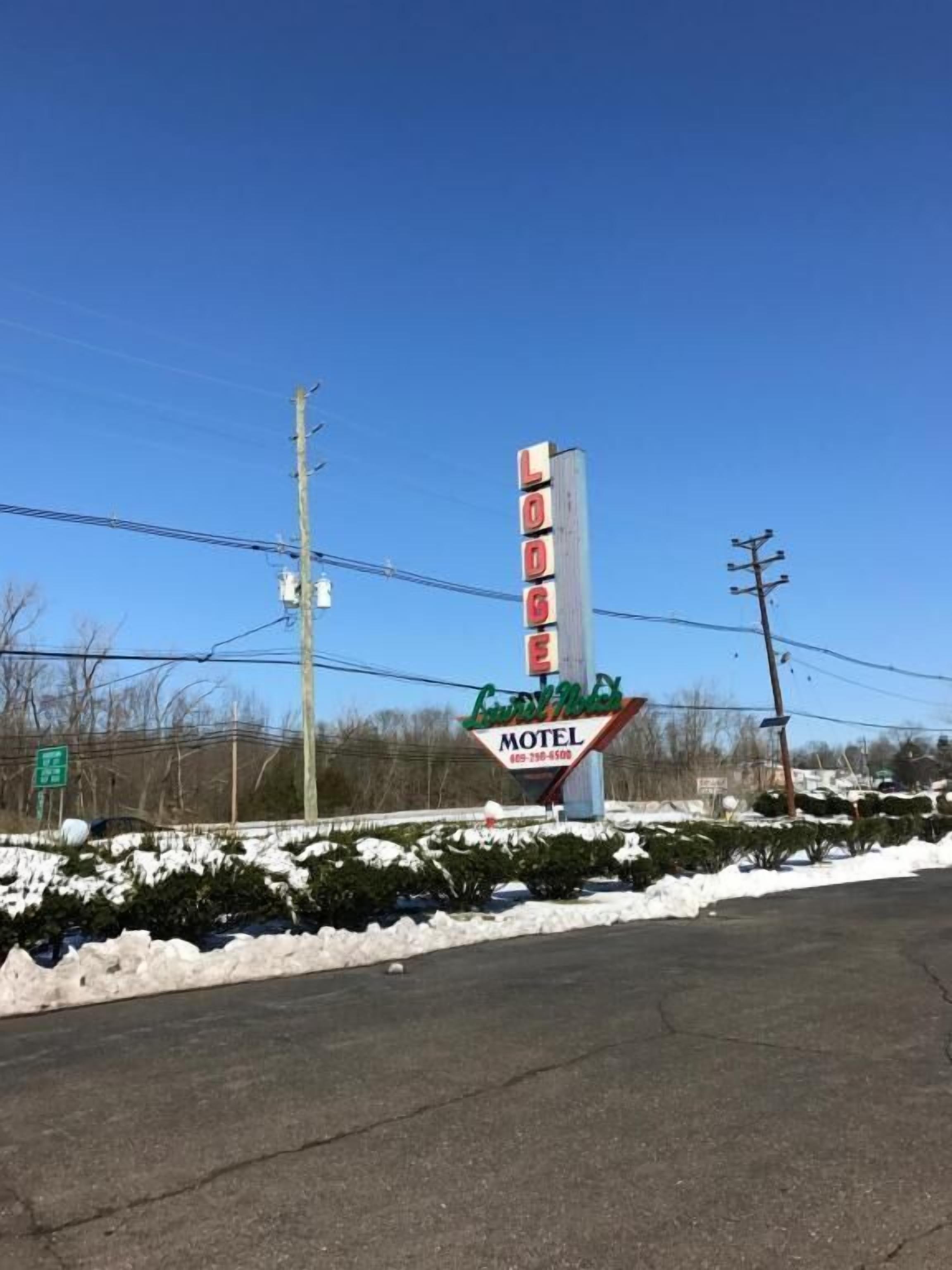 Ein Schild eines Motels, mit einem 'Lodge'-Logo und einem Schild mit der Aufschrift 'Country Inn Motel' darunter.