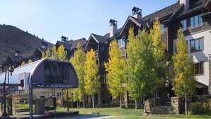 A mountain lodge with a covered bus stop, wooden buildings, and autumn foliage. - Beaver Creek Landing Condo 202 (Avon)