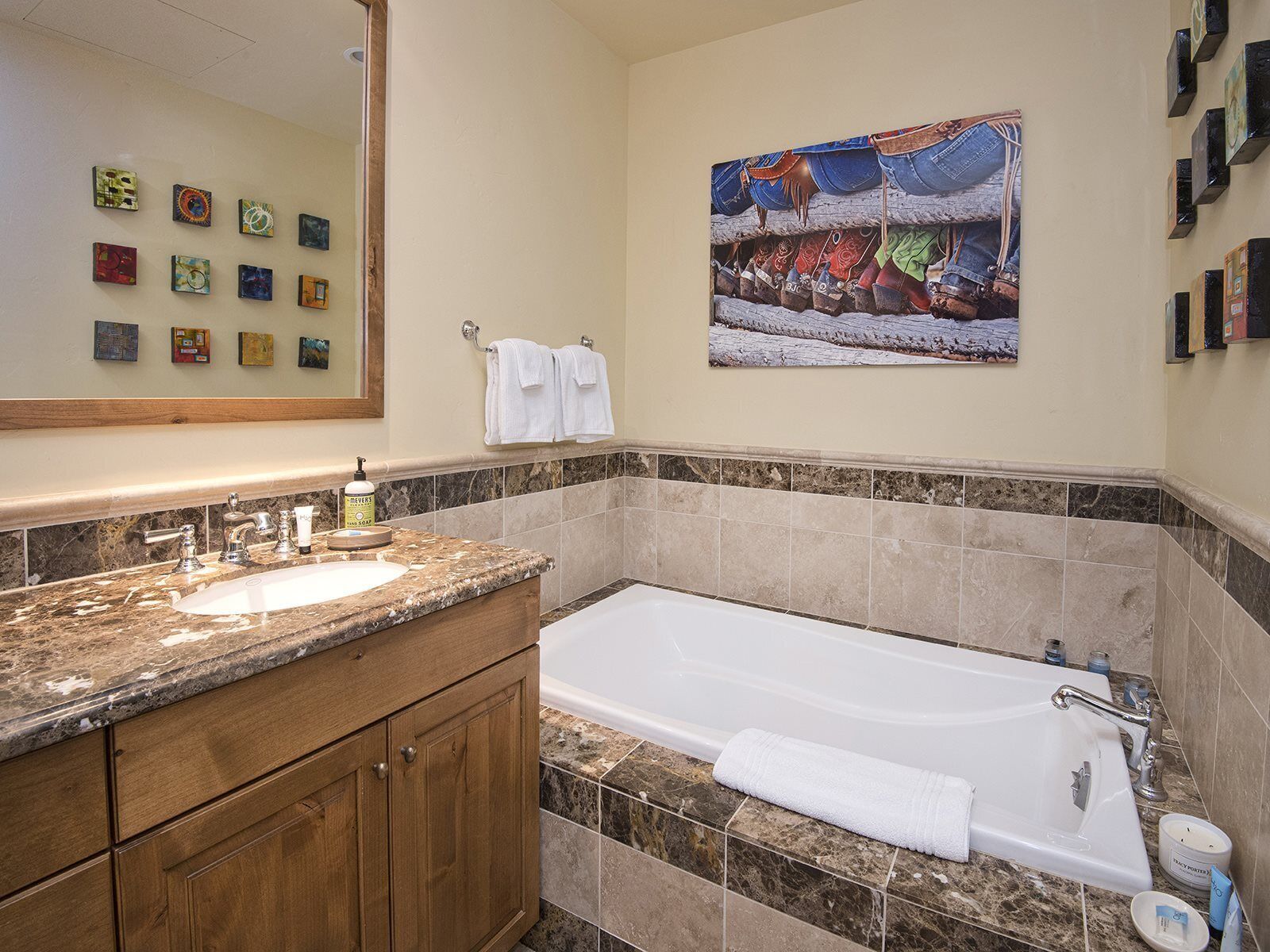 A bathroom with a marble countertop, a bathtub, and a large mirror.