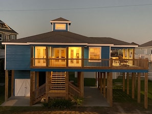 Enjoy waterfront views from the elevated deck with a railing and staircase leading to the entrance.