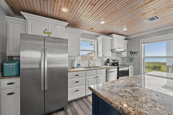 Enjoy cooking in this well-equipped kitchen with stainless steel appliances, white cabinetry, and a spacious granite countertop.