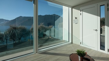 Una habitación moderna con un gran ventanal que da a un balcón con vistas a la montaña.