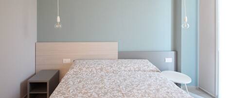 A modern bedroom with a bed, bedside tables, and a small table by the window.