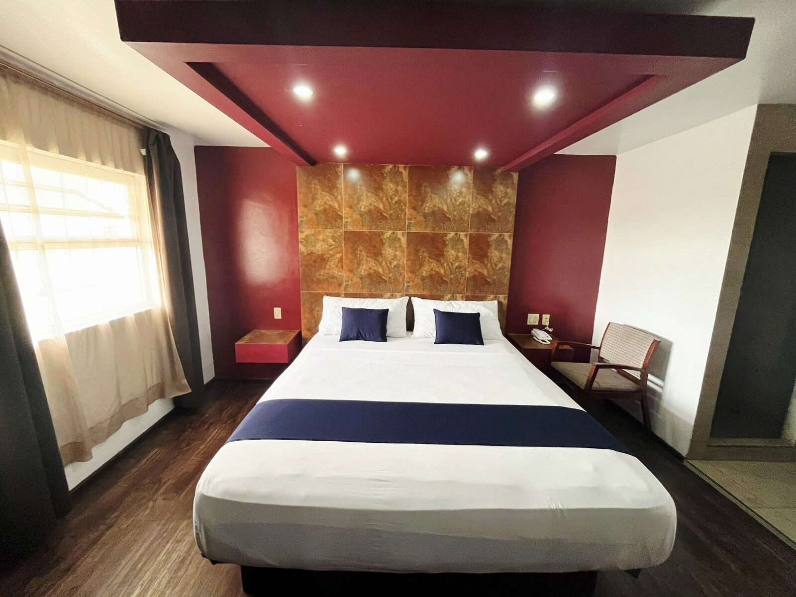 Ein Hotelzimmer mit einem großen Bett, einem Nachttisch, einem Sessel und einer Marmorwand.
