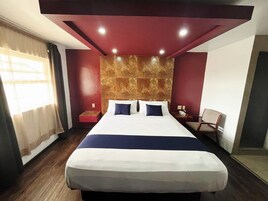 Una habitación de hotel con una cama grande, una mesita de noche, una silla y una pared de mármol.
