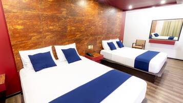 A hotel room with two beds, a wooden accent wall, a mirror, and a wooden floor.