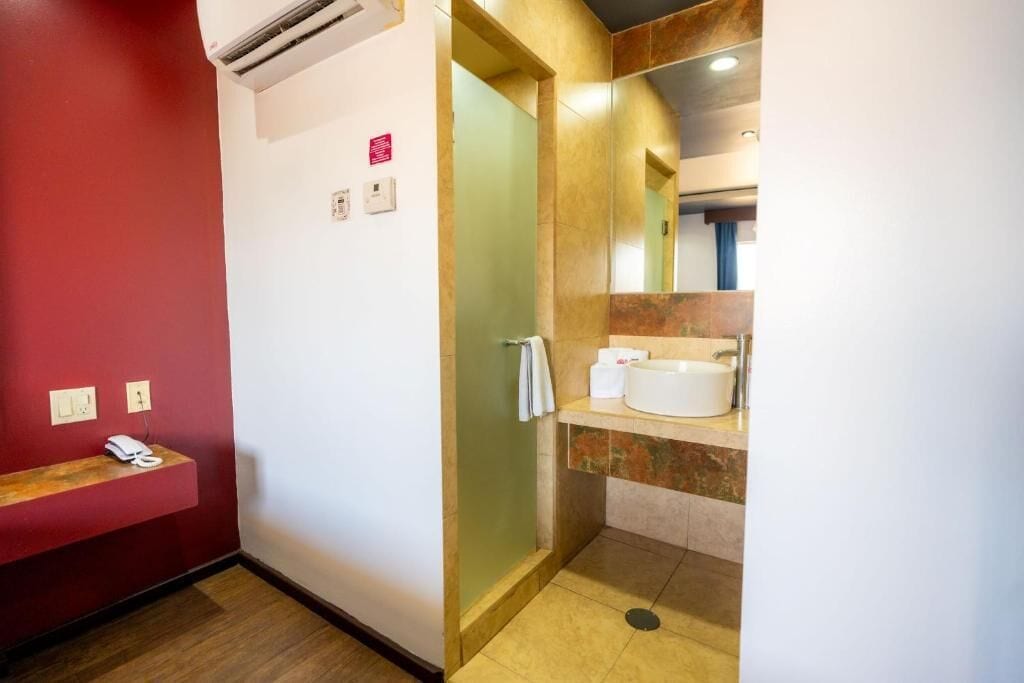 A hotel bathroom with a shower, sink, and a mirror.