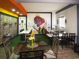 Un restaurante con pared de piedra, un mural y una mesa verde con sillas.