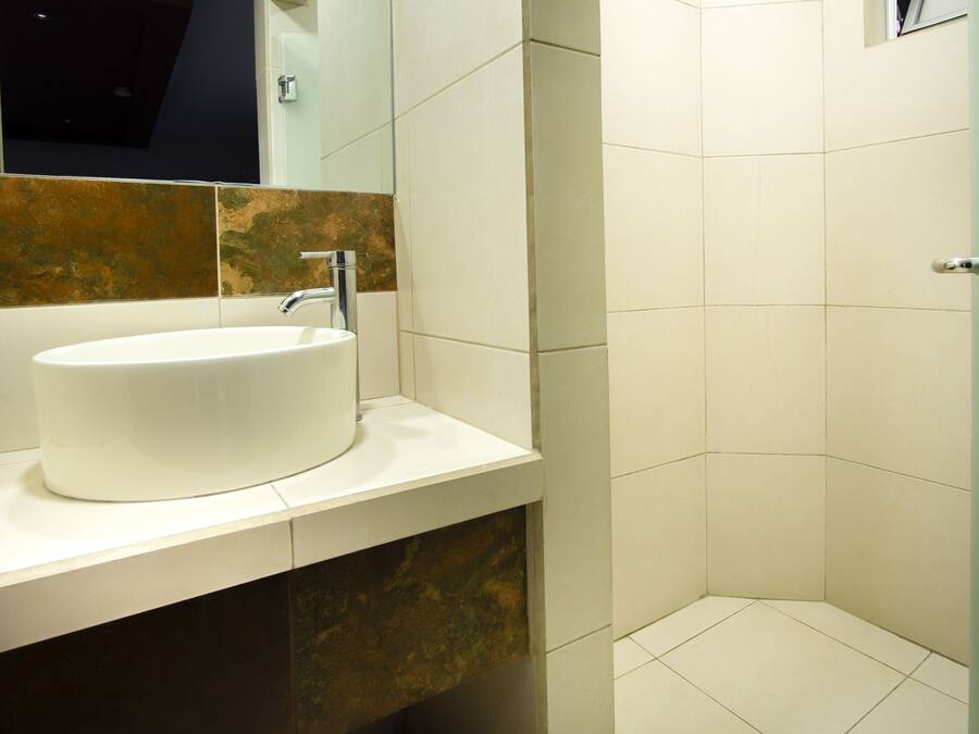 Uma casa de banho moderna com uma pia branca, um espelho e uma área de duche.
