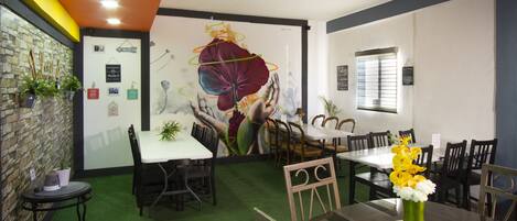 Un restaurante con un mural, alfombra verde y mobiliario de madera.