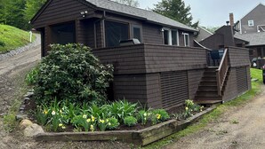 A two-story wooden building with a covered porch and a staircase leading to the upper floor. - Newfound Lake, Bristol NH Lakefront Cottage (Bristol)