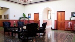 A room with a patterned carpet, wooden doors, and dark upholstered chairs. - Britannia (San José)