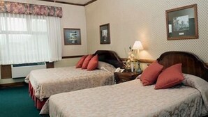A hotel room with two beds, a nightstand with a lamp, and framed pictures on the wall. - Britannia (San José)
