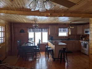 Cozy cabin interior with a central dining area, kitchen, and wooden floors.