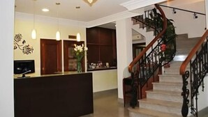 A reception area with a counter, a chandelier, and a staircase with a wooden handrail. - Las Nieves (Granada)