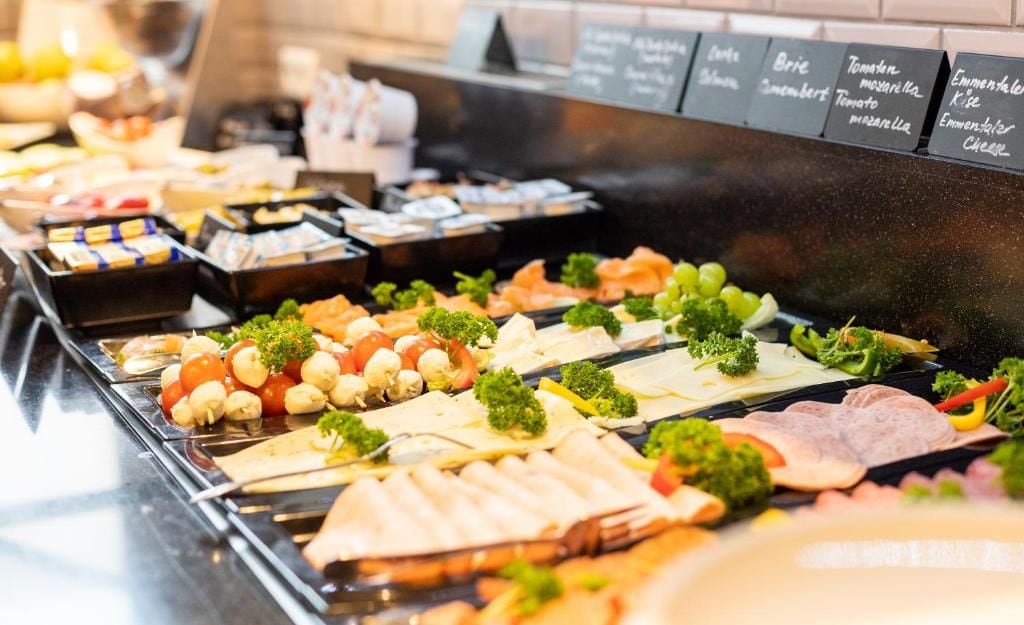 Un buffet proposant une variété de plats, notamment des viandes, des fromages et des légumes.