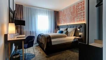 A hotel room with a bed, desk, chair, and a large window with curtains.